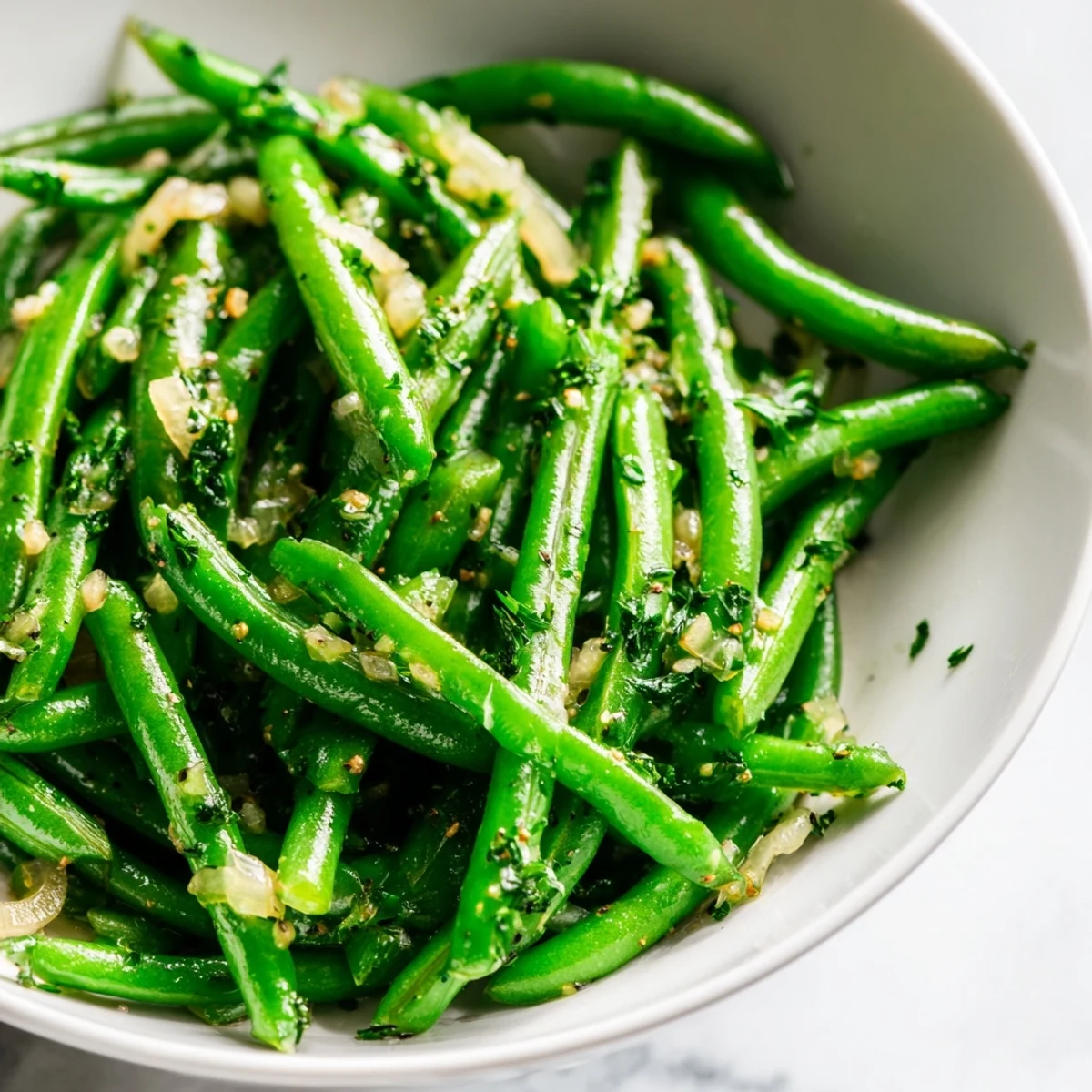 Bright green beans glistening in garlic butter with caramelized shallots, served as a savory side dish.