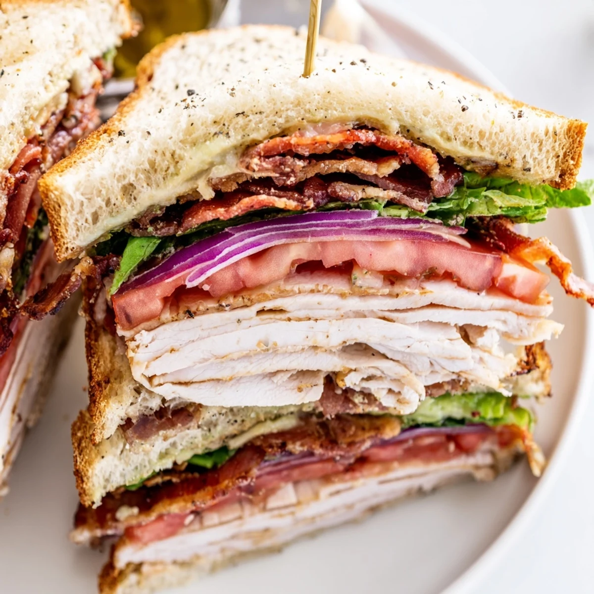 Golden toasted bread layers show roasted turkey, crisp beef bacon, lettuce, and tomato on the Turkey Club Sandwich.