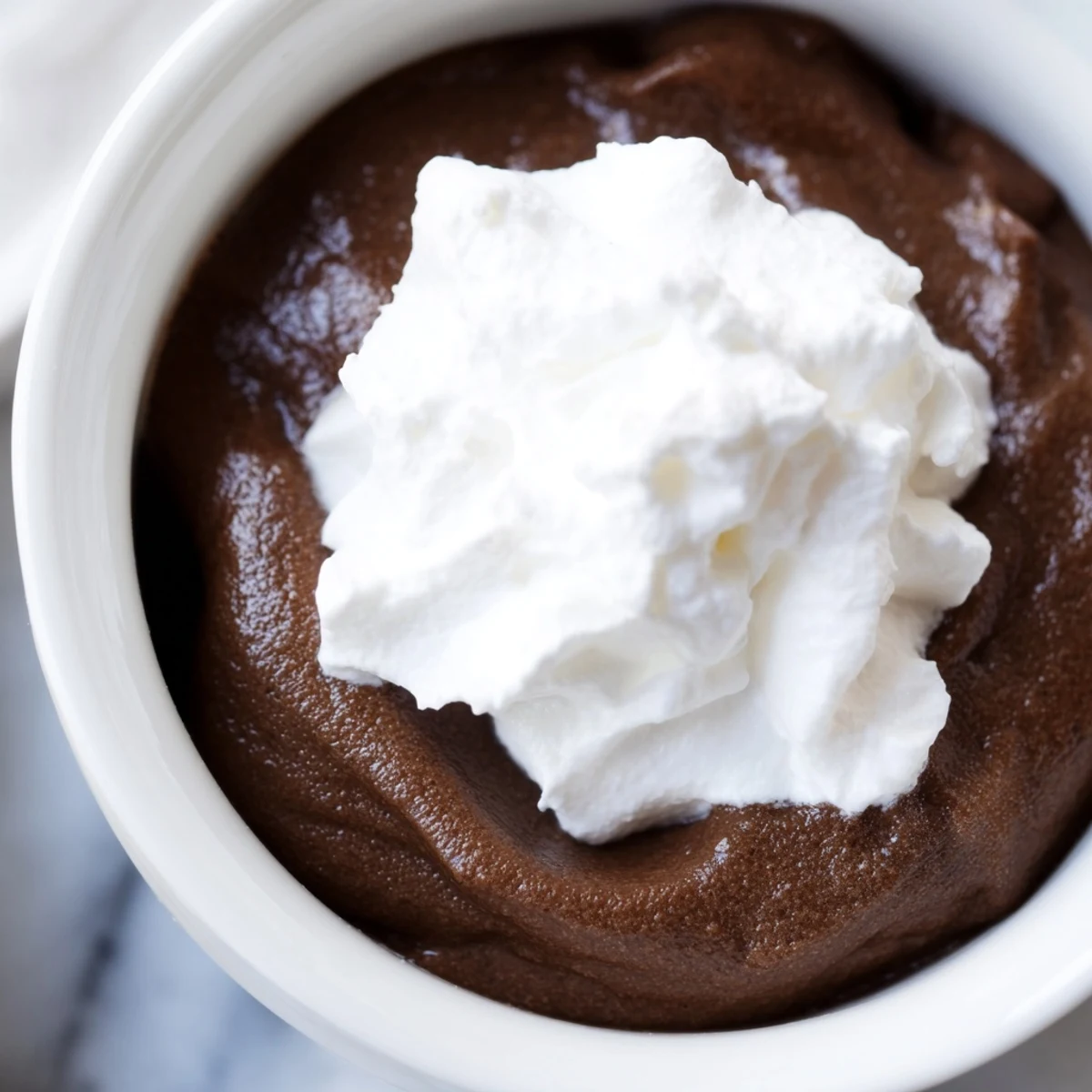 Freshly whipped cream topping on a chilled chocolate pudding, served as an indulgent American dessert.