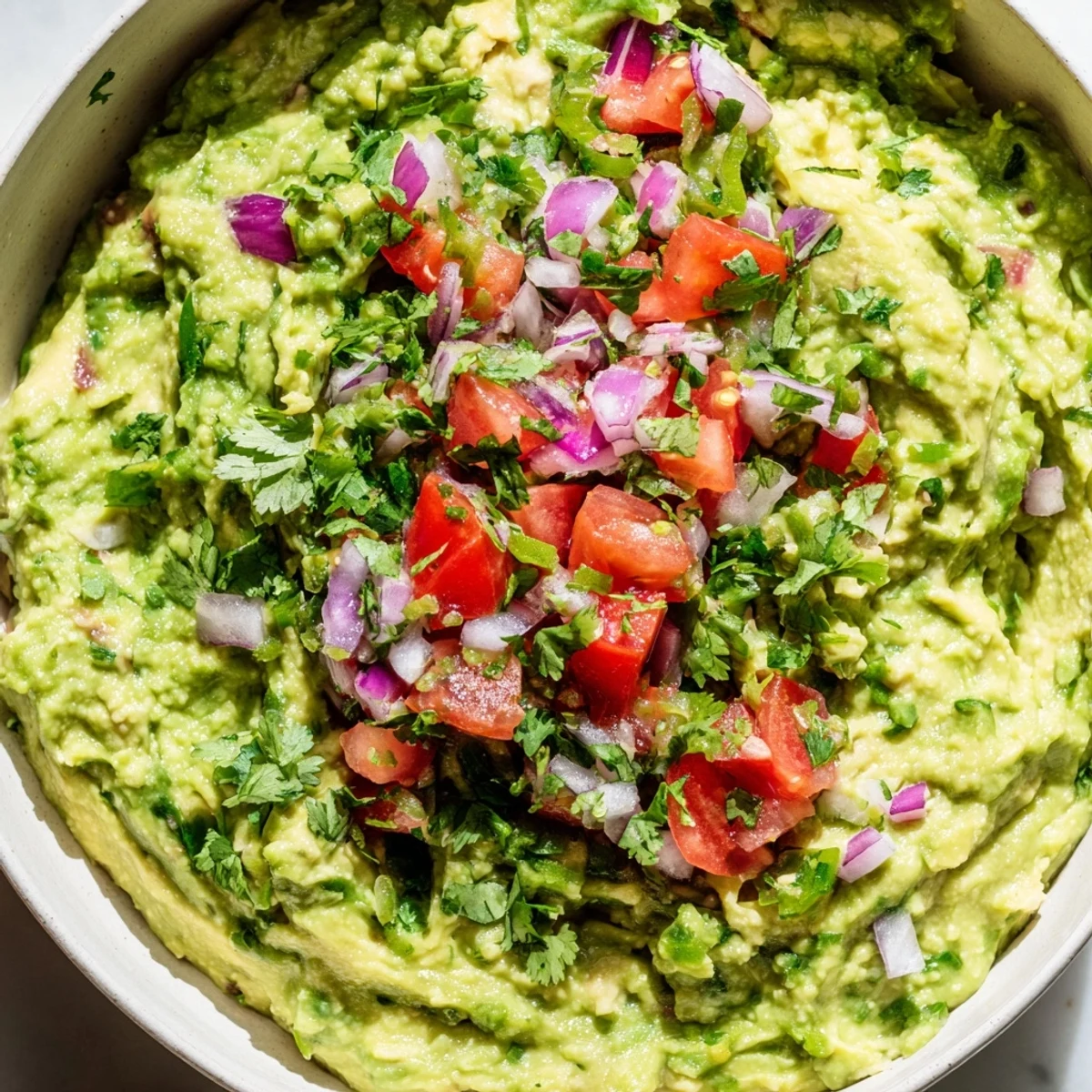 Colorful Game Day Guacamole layered with vibrant red salsa, fresh avocado, and diced jalapeños, ready for a festive appetizer spread on game day.