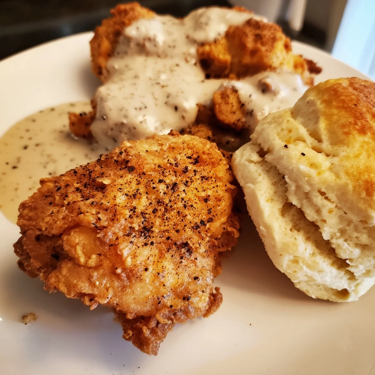 A platter of crispy buttermilk-fried chicken, flaky biscuits, and rich homemade gravy, ready to serve.  
