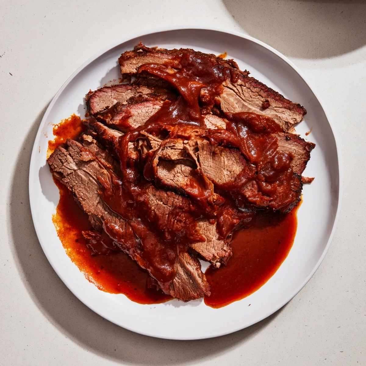 Slow Cooked Beef Brisket with Smoky BBQ Sauce is garnished with onions and served with pickles.