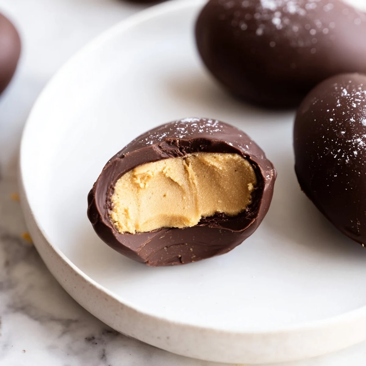 Rich chocolate enrobed Chocolate Peanut Butter Eggs on a cooling rack with sprinkles.