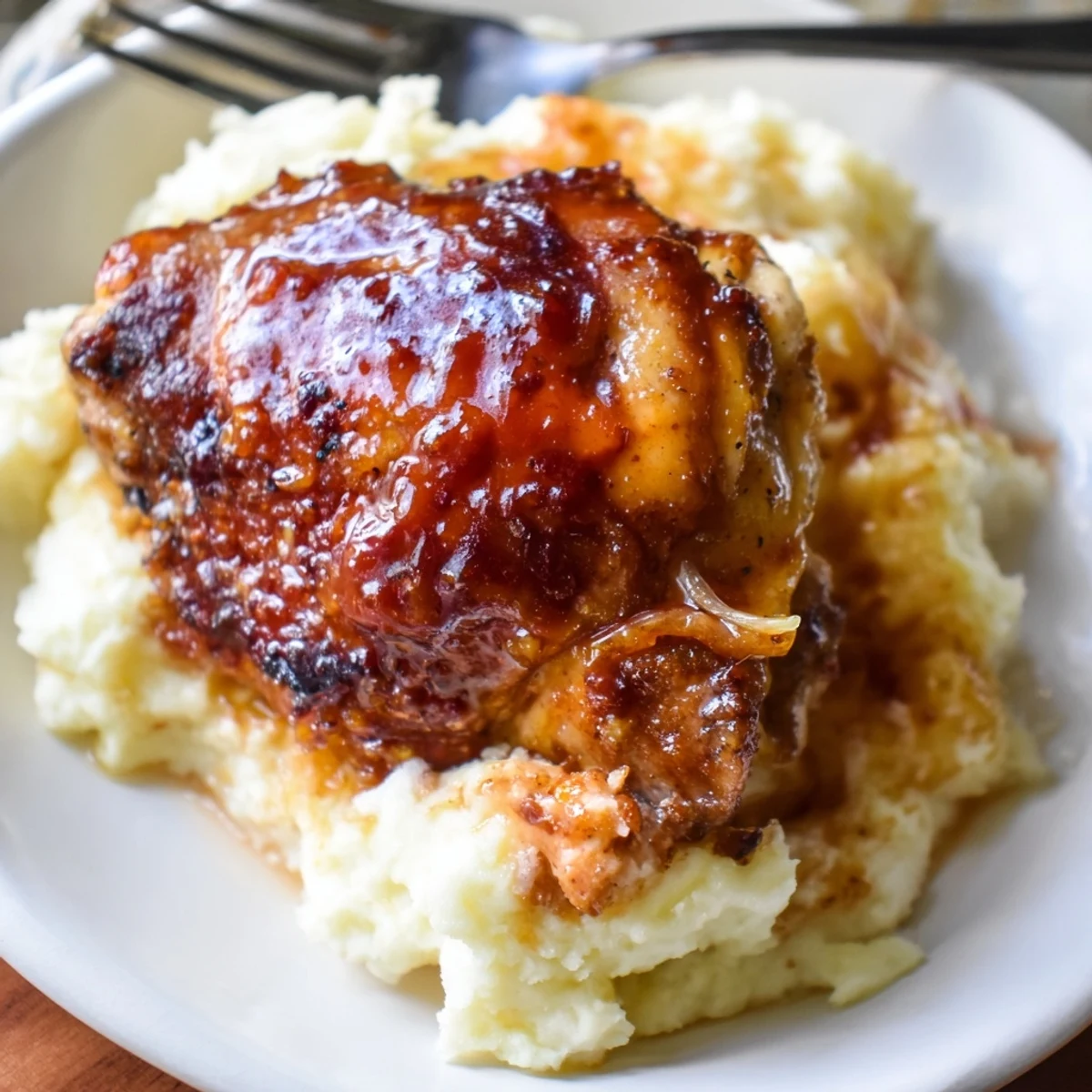 Golden-brown chipotle honey chicken thighs rest beside creamy smoked Gouda mashed potatoes garnished with fresh chives.