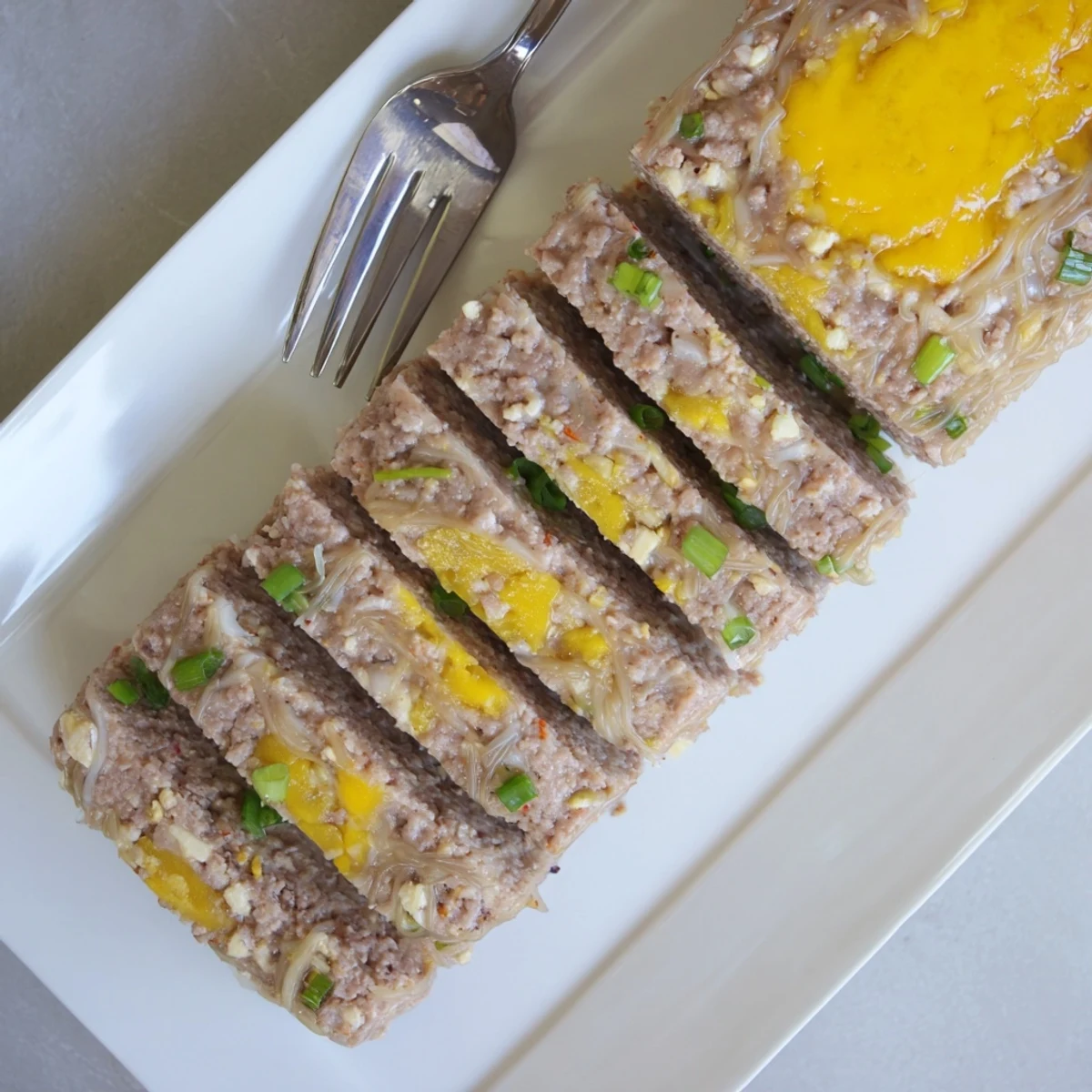 Steamed pork and egg meatloaf Cha Trung Hap glistening in a white dish, ready to slice and serve with jasmine rice.