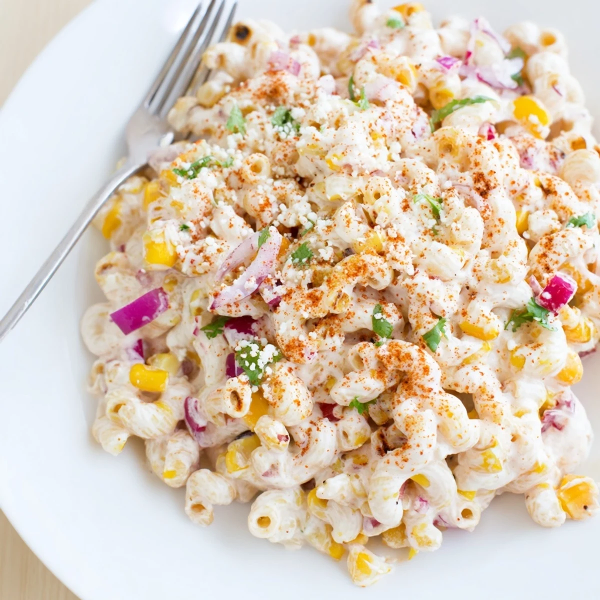 Creamy Mexican Street Corn Pasta Salad served chilled, mixed with rotini, red onion, jalapeños, and fresh lime wedges.