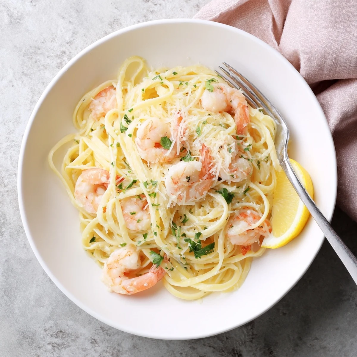 Creamy shrimp scampi garlic pasta in a skillet with lemon wedges and grated parmesan