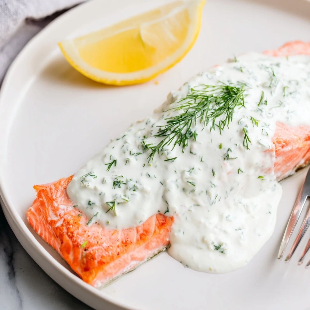 Golden pan-seared Mediterranean salmon fillets drizzled with creamy lemon dill yogurt sauce and fresh herbs