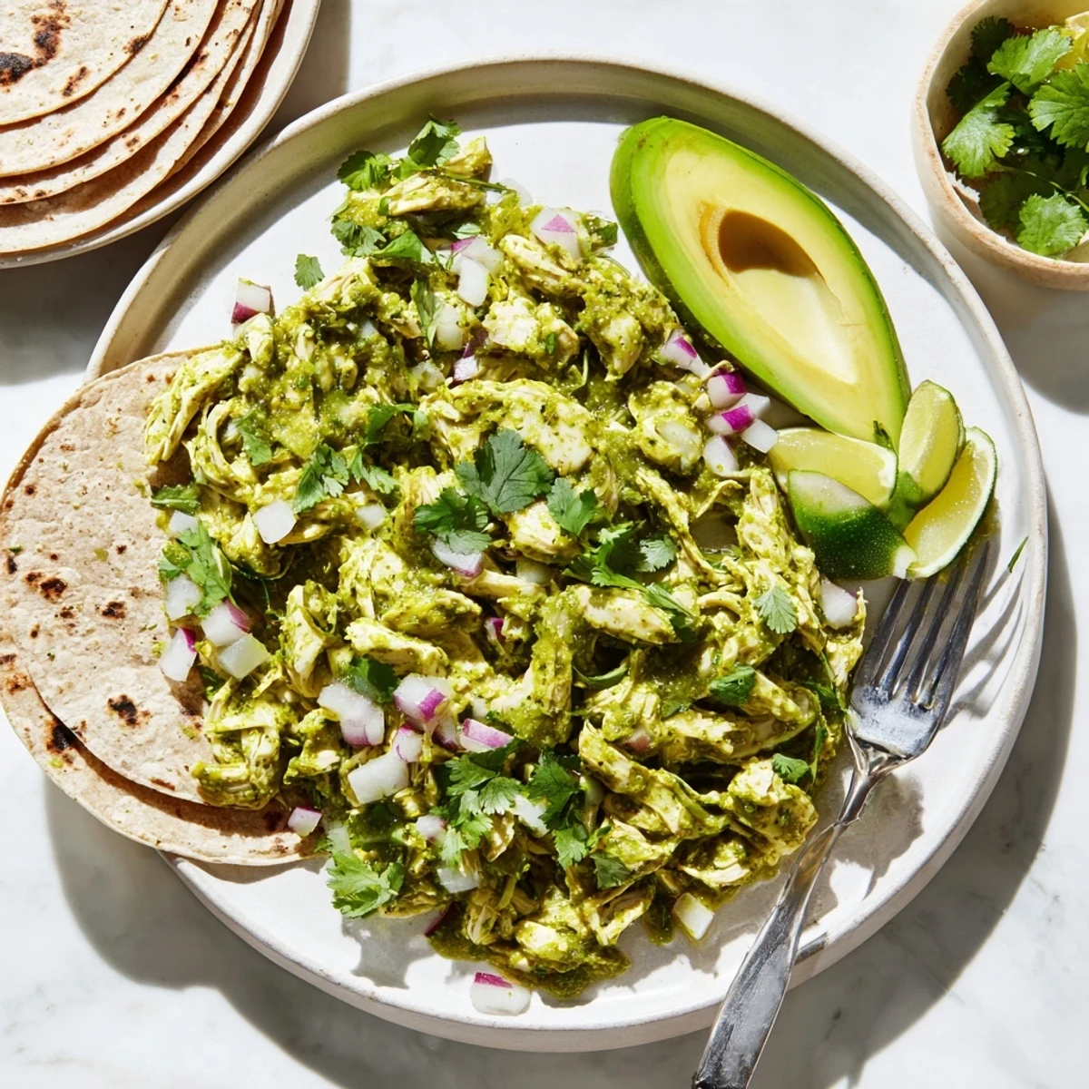Tangy salsa verde chicken shredded and nestled in warm corn tortillas with fresh cilantro