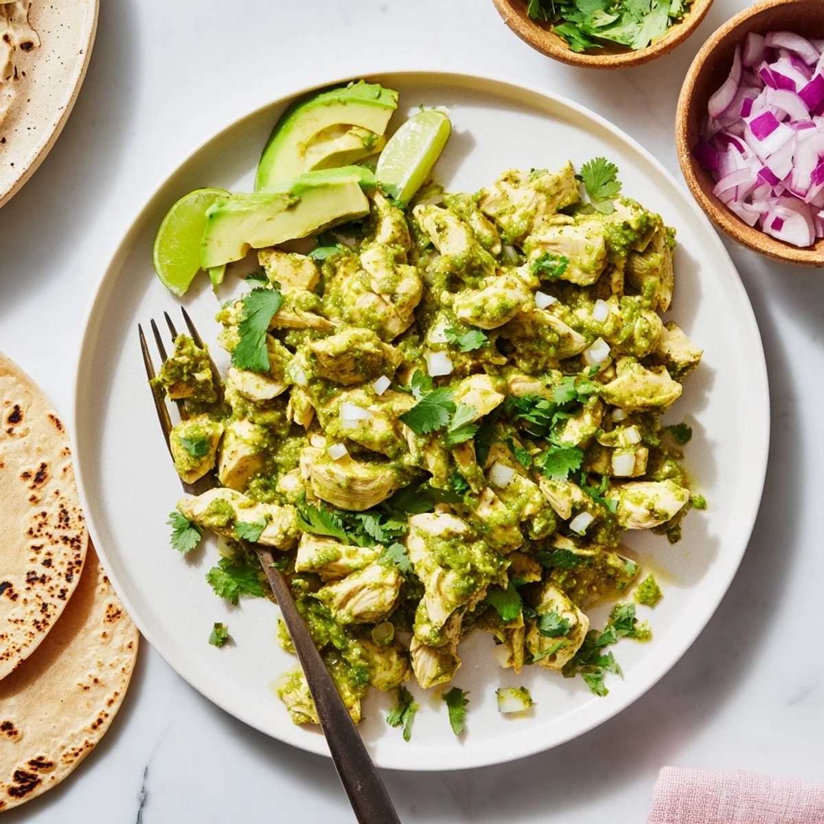Salsa verde chicken tacos garnished with lime wedges and creamy avocado for Taco Tuesday