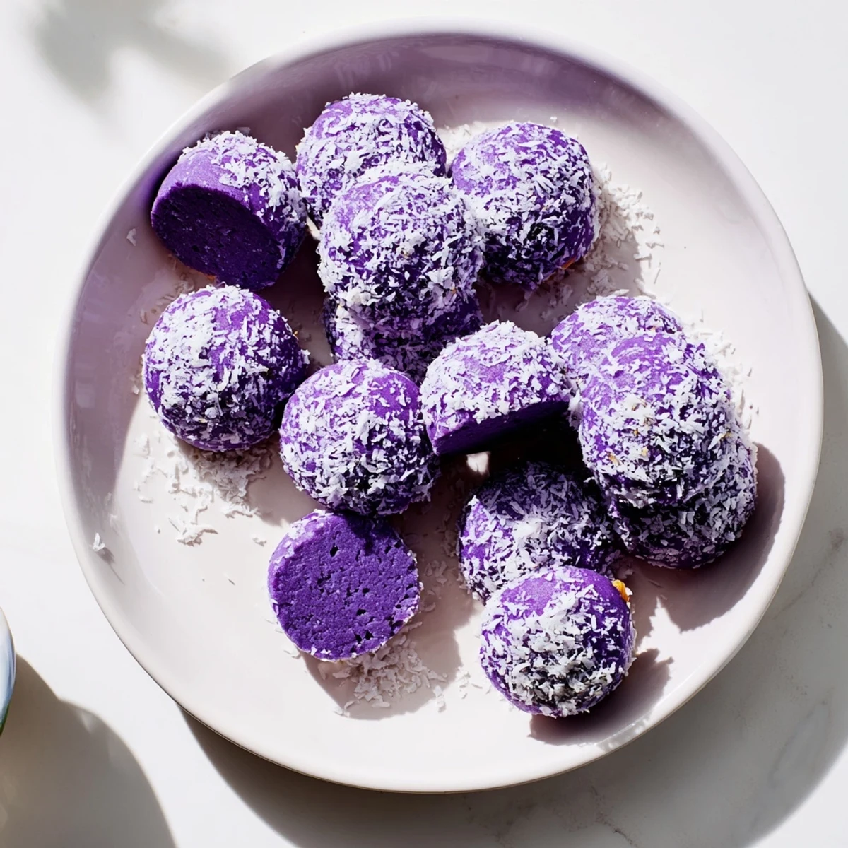Bite-sized Coconut Ube Besito cookies with purple centers finished with toasted coconut topping