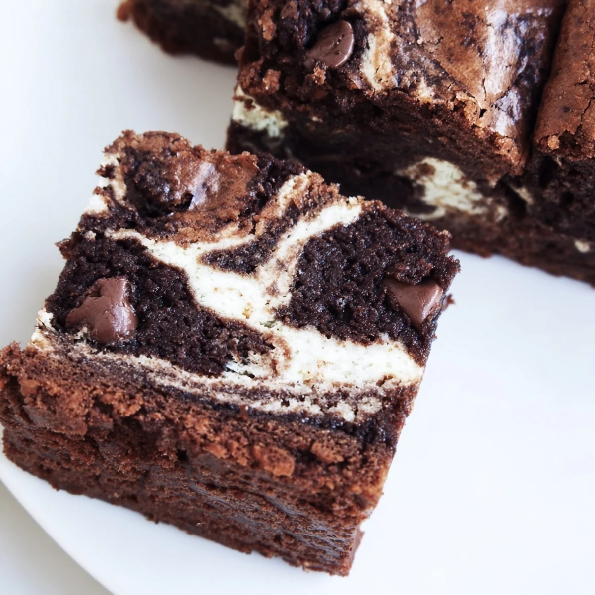 Fudgy cottage cheese brownies with creamy swirl topping on a white serving plate