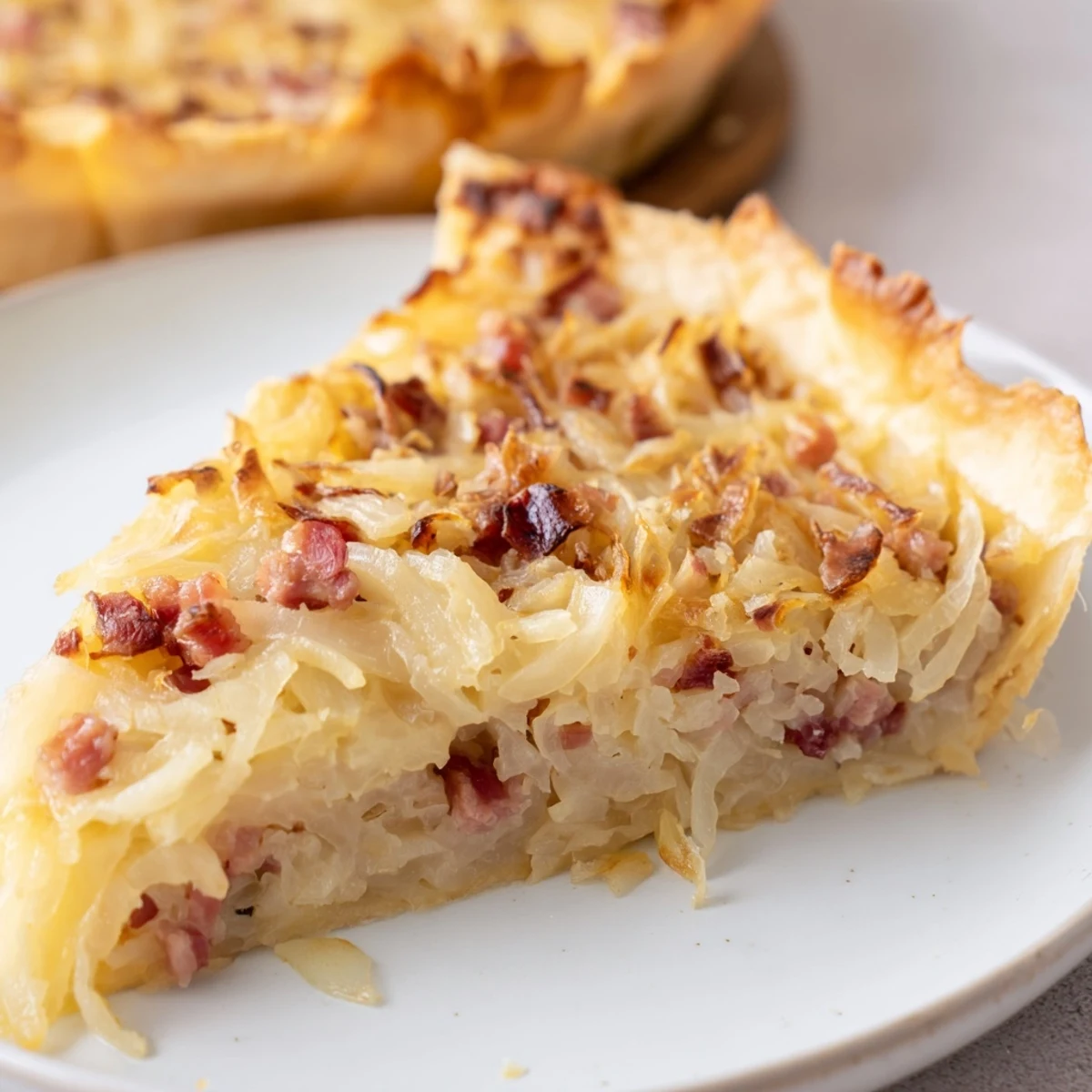 Homemade German onion pie slice with smoky bacon, sweet onions, and melted cheese on flaky crust