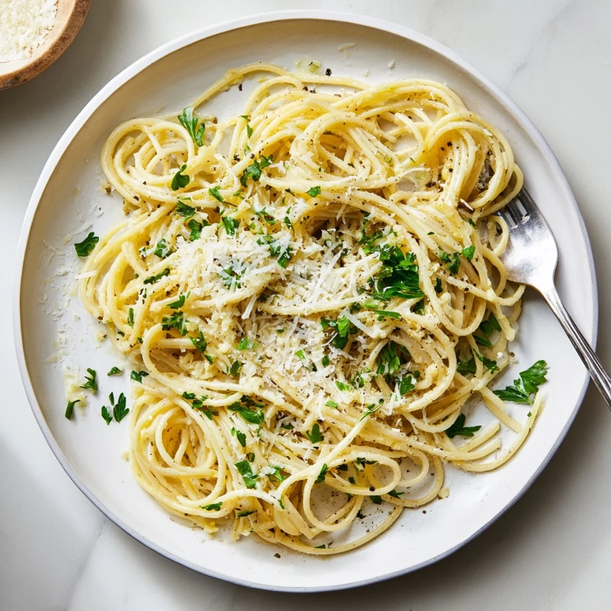 Golden garlic butter pasta coated in glossy sauce with fresh parsley garnish and parmesan cheese