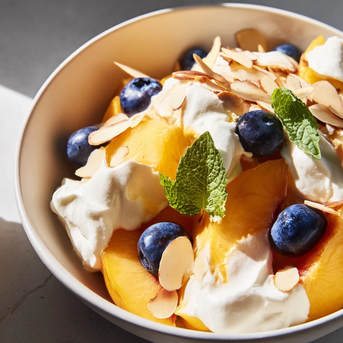 Sliced ripe peaches layered with fluffy whipped cream and blueberries for a refreshing summer dessert