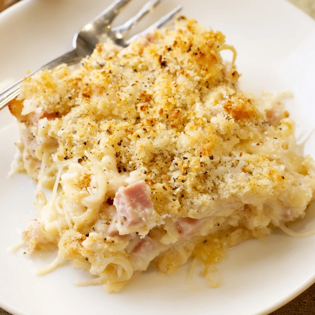 Sliced serving of Chicken Cordon Bleu Casserole Recipe steaming, creamy Dijon sauce visible