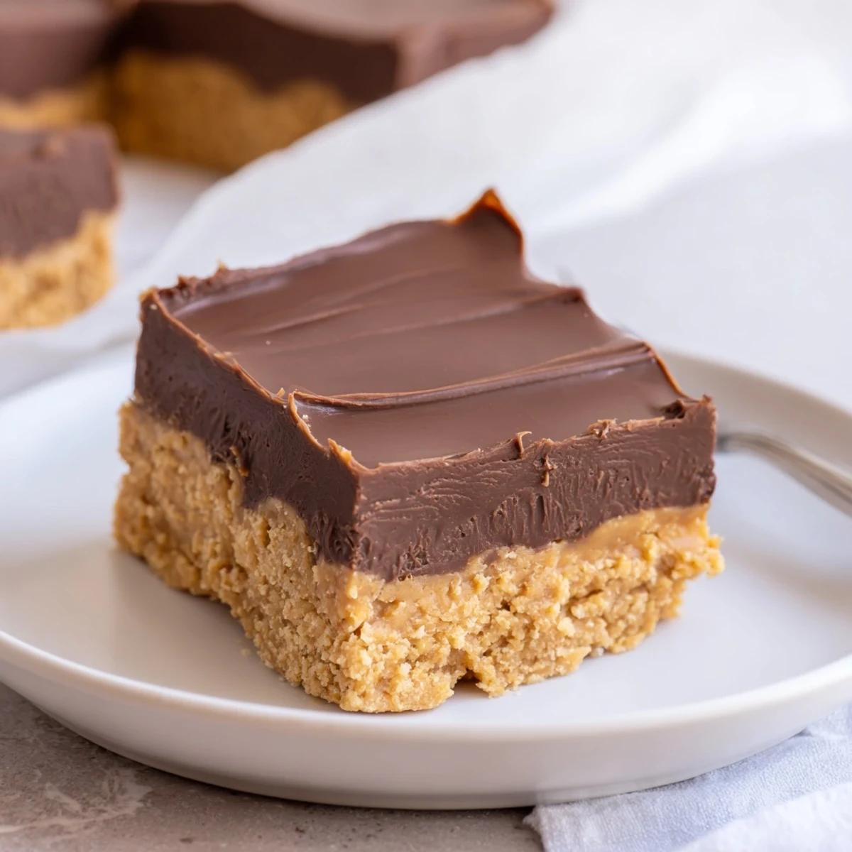 No Bake Peanut Butter Bars chilled on parchment, glossy chocolate topping, peanut aroma