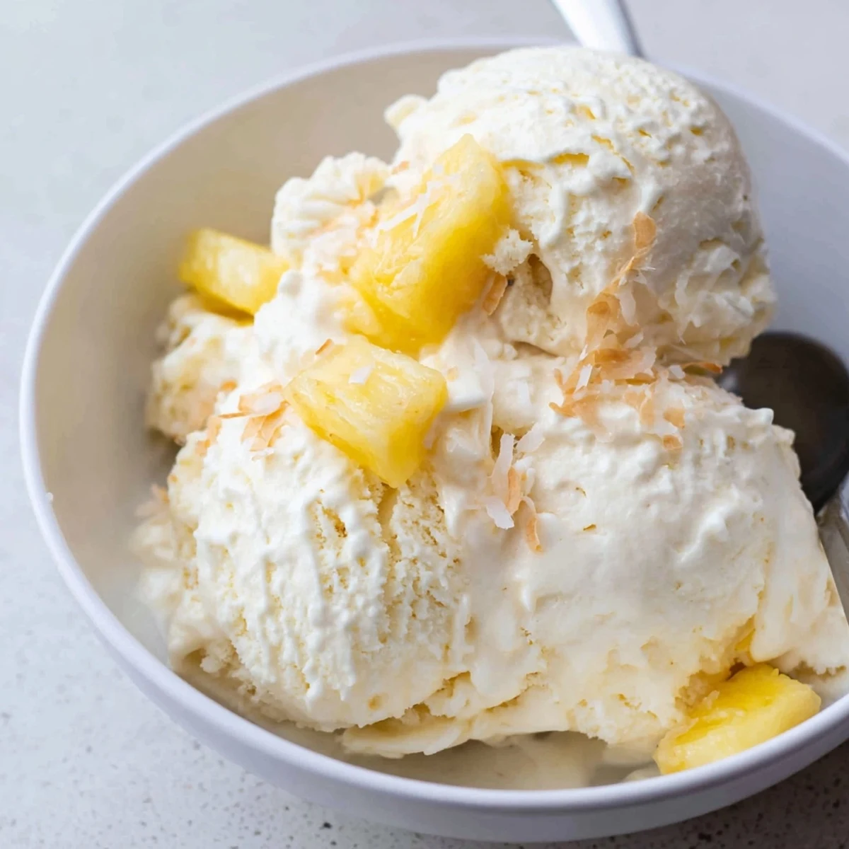 Creamy Pineapple Ice Cream scoops glistening, tropical aroma, served in bowl