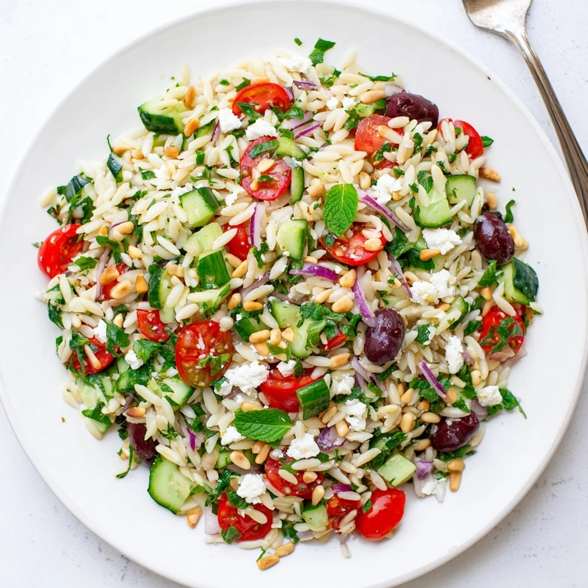 Bountiful bowl of Mediterranean orzo power salad featuring cherry tomatoes, olives, and crumbled feta