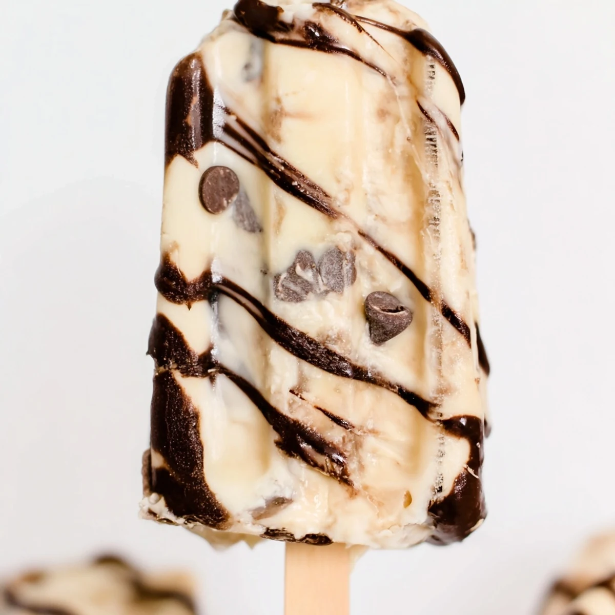 Creamy chocolate banana bliss popsicles with marbled swirls on a wooden popsicle stick