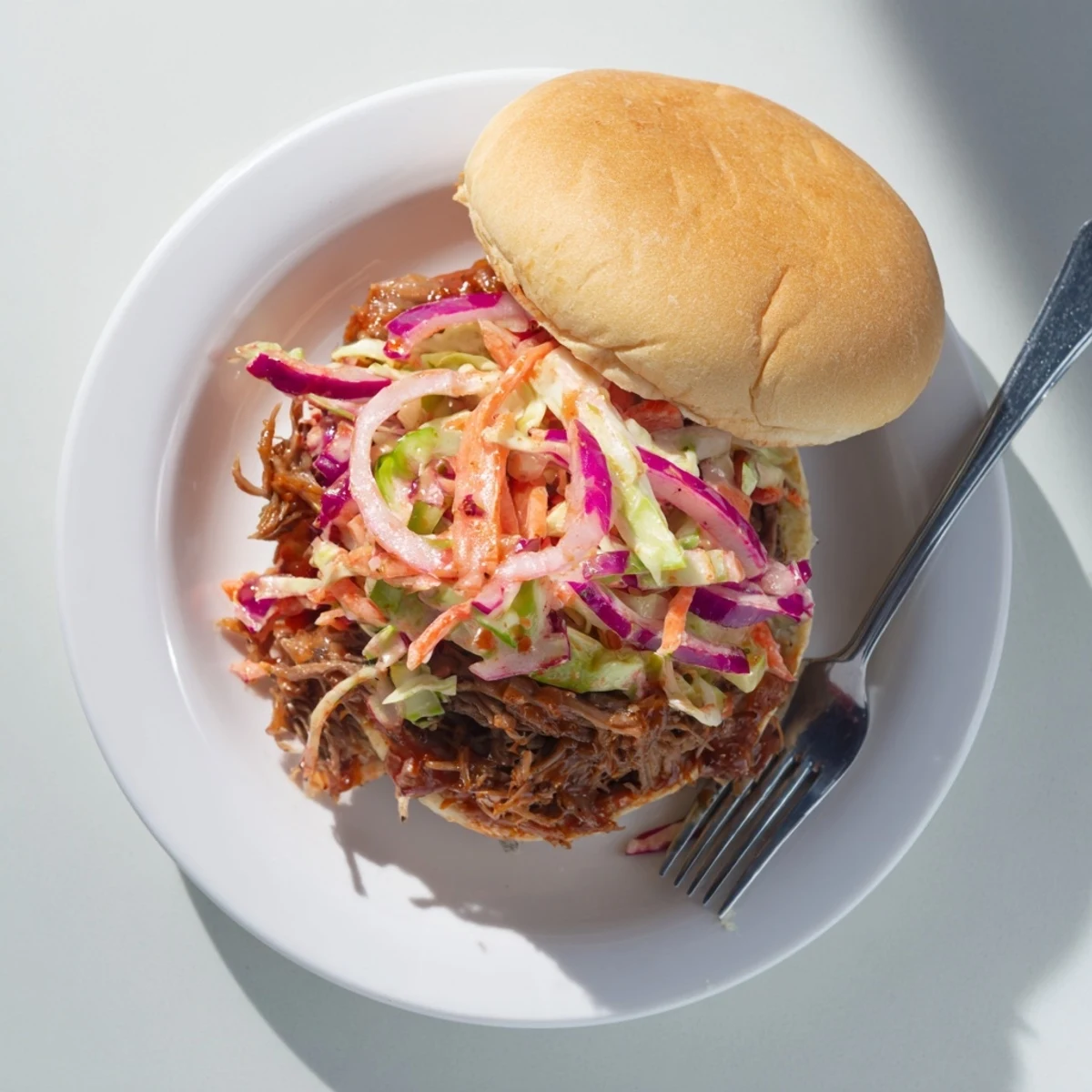 Savory shredded BBQ beef roast layered on soft sandwich buns topped with tangy crunchy coleslaw