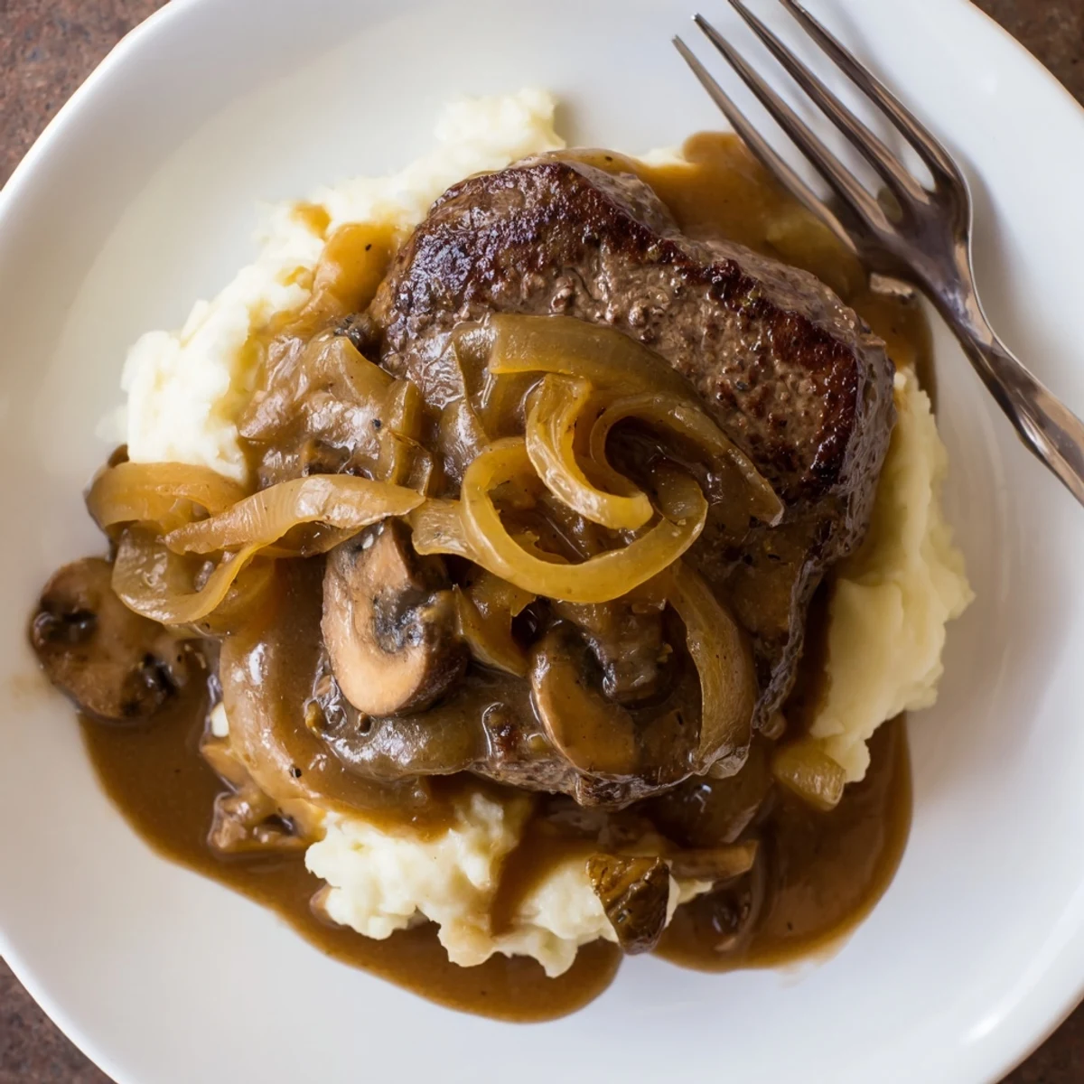 Hearty plate of mashed potatoes topped with steaming Country Style Smothered Cube Steak Recipe