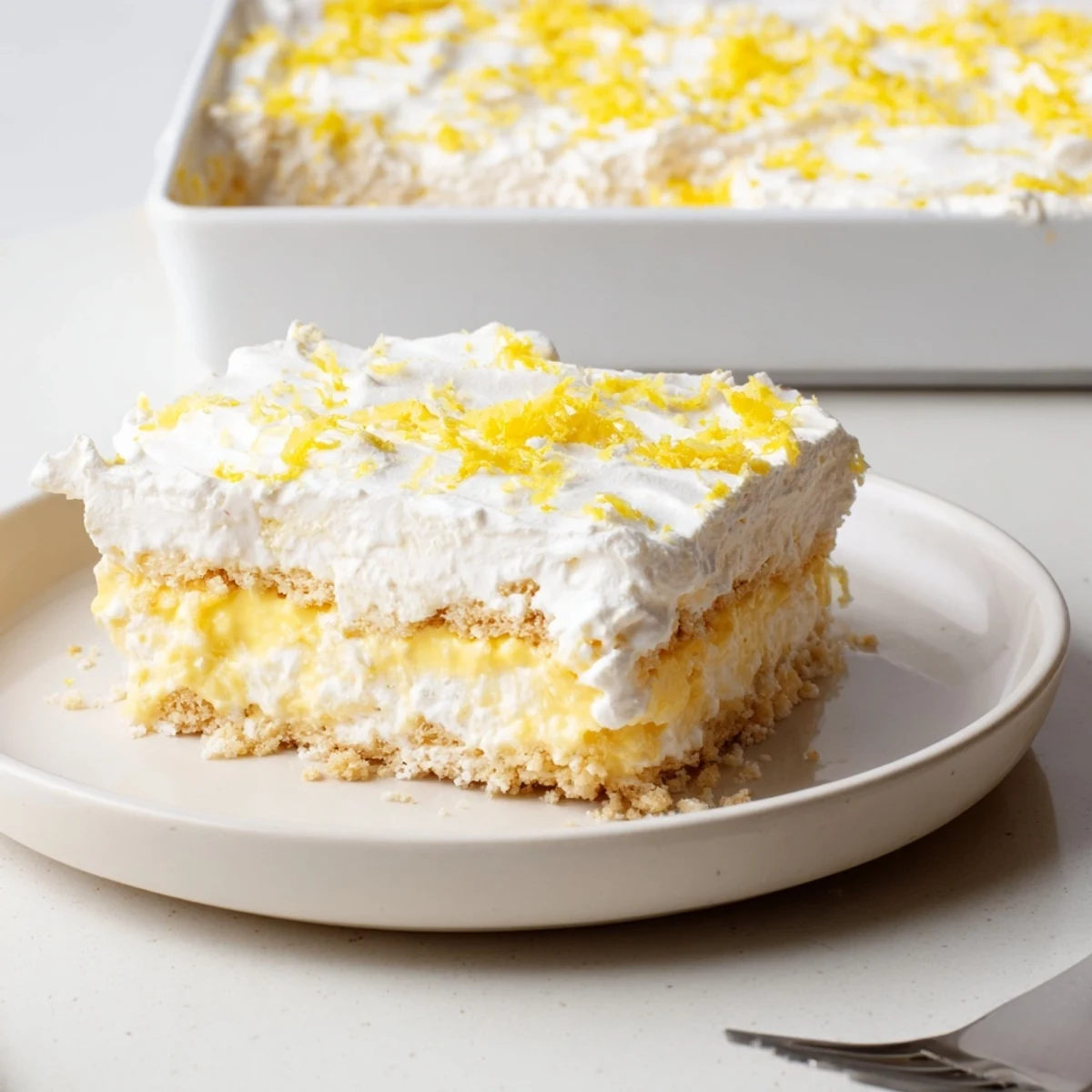 Fork-ready Lemon Lush Cake reveals buttery cookie crust, tart lemon pudding and airy topping.