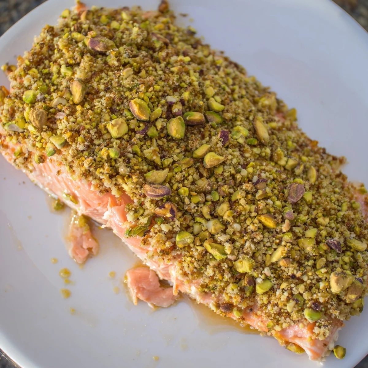 Golden maple pistachio salmon fillet with a crunchy nut crust on a parchment-lined baking sheet