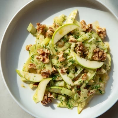 Fresh Apple and Celery Salad with Walnuts served in a white bowl, topped with chopped parsley and a light lemony vinaigrette.  