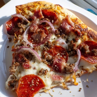 A close-up of a meat lover pizza with beef toppings, featuring bubbling cheese and fresh herbs on a rustic board.